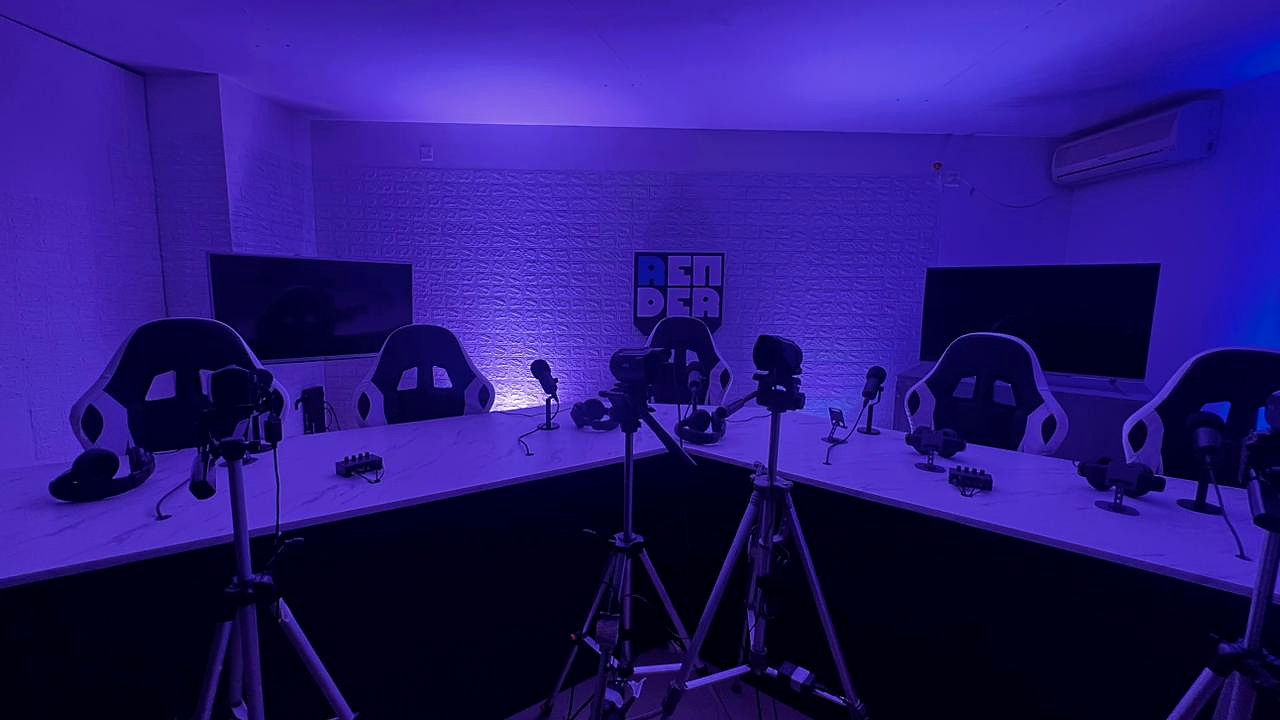 Vista completa del estudio: mesa en U, sillas, micrófonos, cámaras en trípodes y el logo de Render